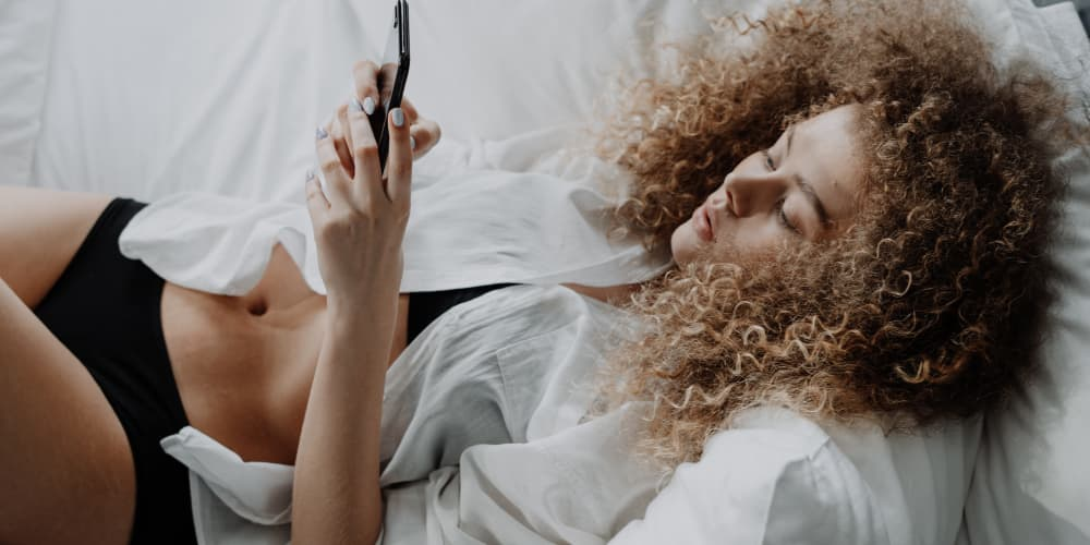 Woman on her phone communicating about long-distance BDSM