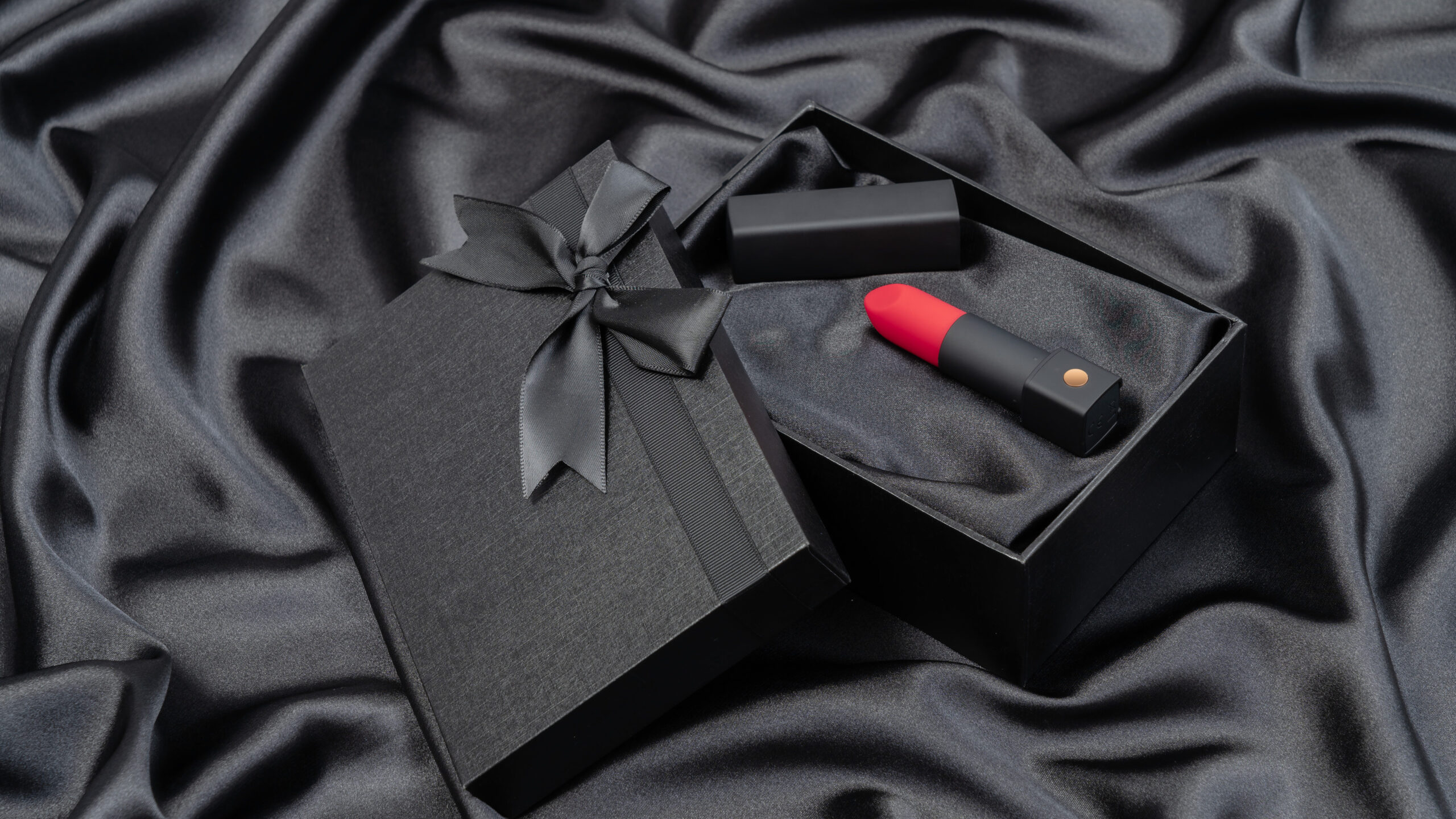 Lovense exomoon lipstick vibrator in black box on black satin background
