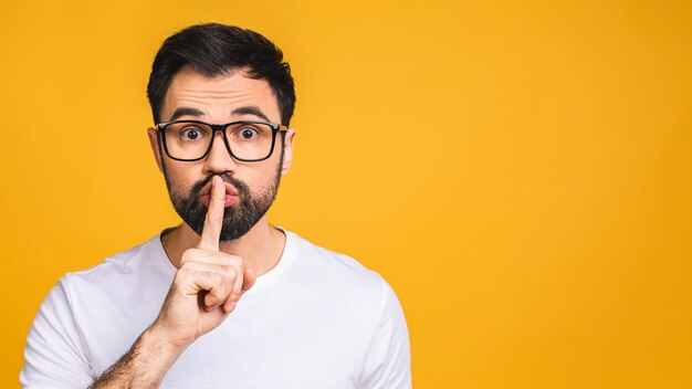 Alt: Man wearing glasses with his index finger on his lips saying "shh"