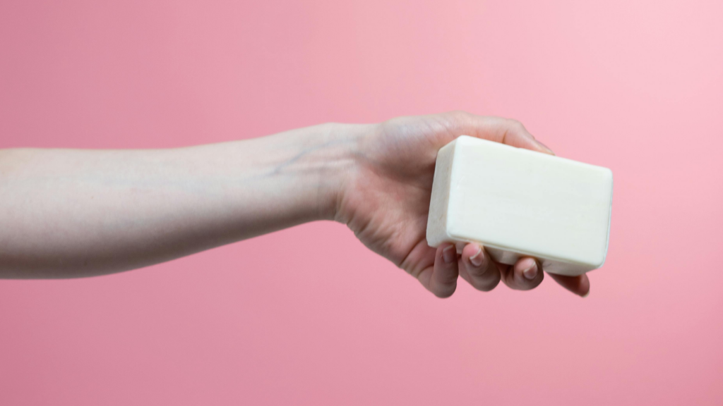 Pink background with hand holding bar of soap