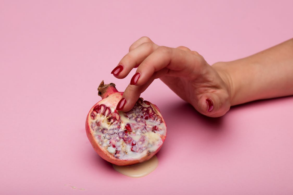 Woman's hand touching leaking pomegranate - used in reference to female masturbation statistics