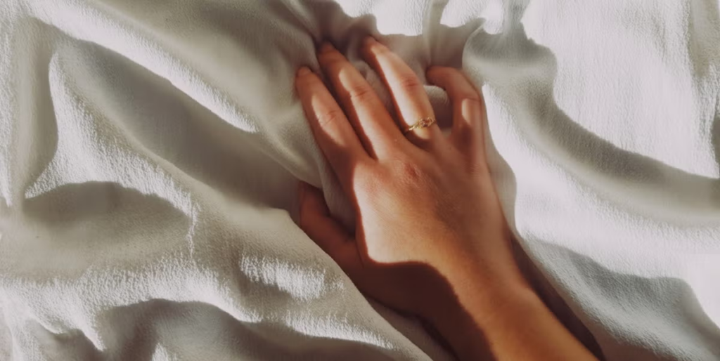 hand resting on white sheets