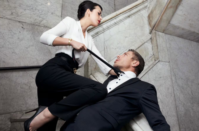 woman dominantly holding a man's tie referencing femdom ideas and play styles